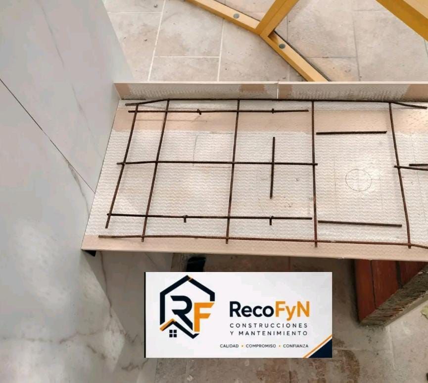 Losa de hormigón con malla de acero de refuerzo y el logotipo de RecoFyN Construcciones en la parte inferior.