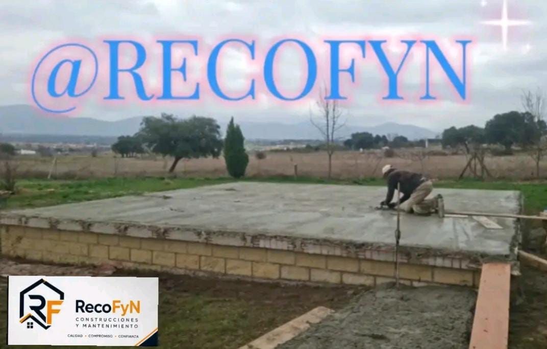 Un trabajador alisa una losa de hormigón en una obra, con el texto @RECOFYN superpuesto.