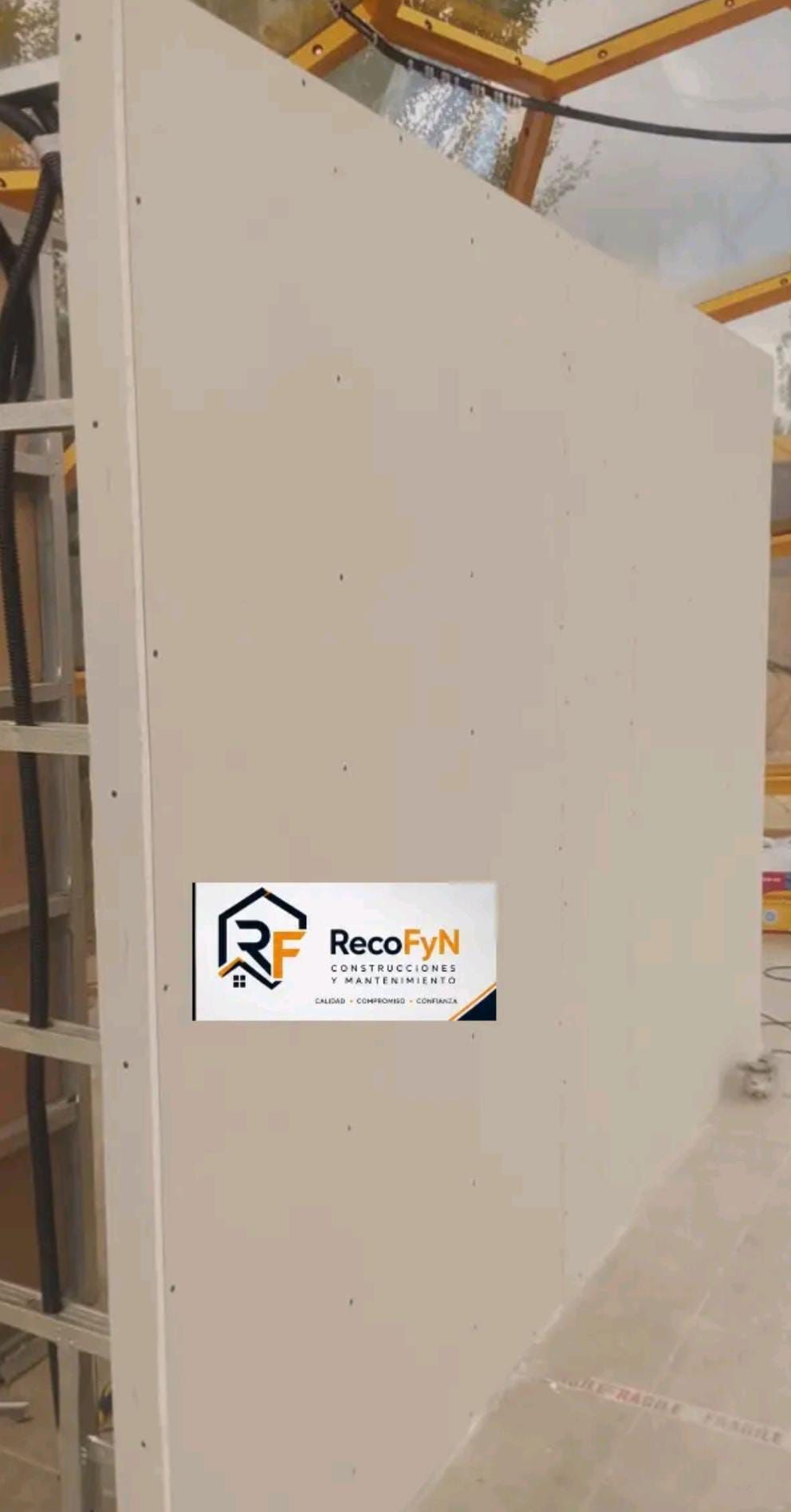 Gran panel o armario industrial de color beige en un almacén, con una pequeña etiqueta con el logotipo en la parte inferior izquierda.