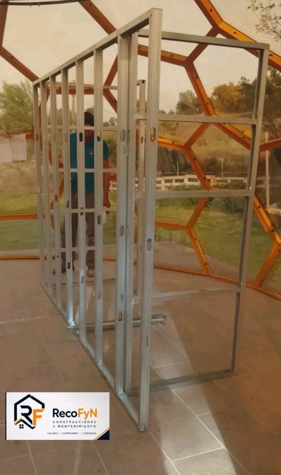 Estructura metálica de andamio con un trabajador visible a través de ella en una zona de construcción al aire libre.