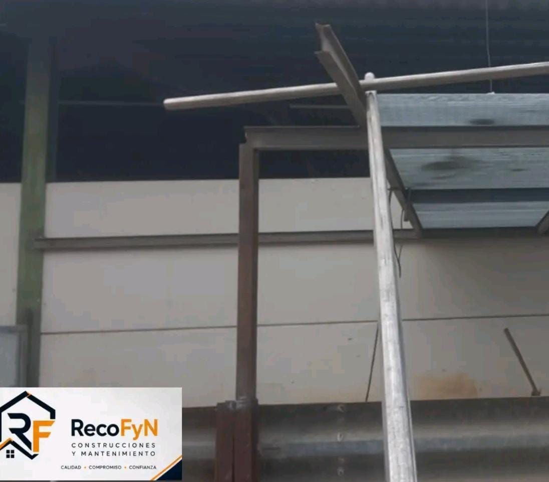 Espacio de trabajo industrial con tuberías metálicas y una estructura de techo inclinado dentro de un edificio tipo almacén.