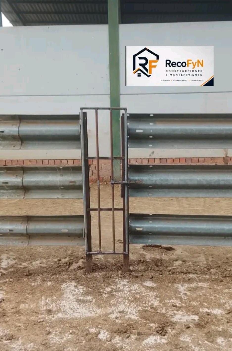 Puerta de seguridad de almacén con barandillas metálicas y un letrero de RecoFYN en la pared.