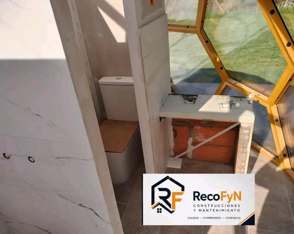 Esquina de pared dañada con estructura interior expuesta y escombros, junto a un marco de ventana amarillo y el logotipo de RecoFyN.