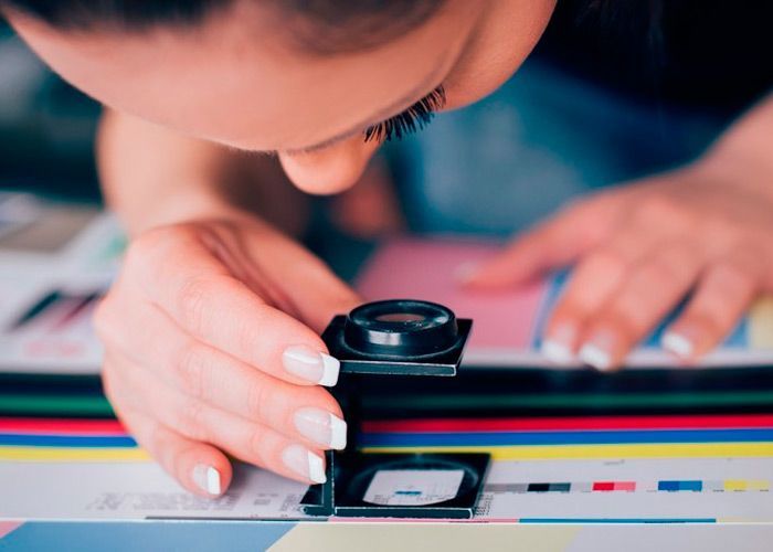 Una mujer mira a través de una lupa un trozo de papel.