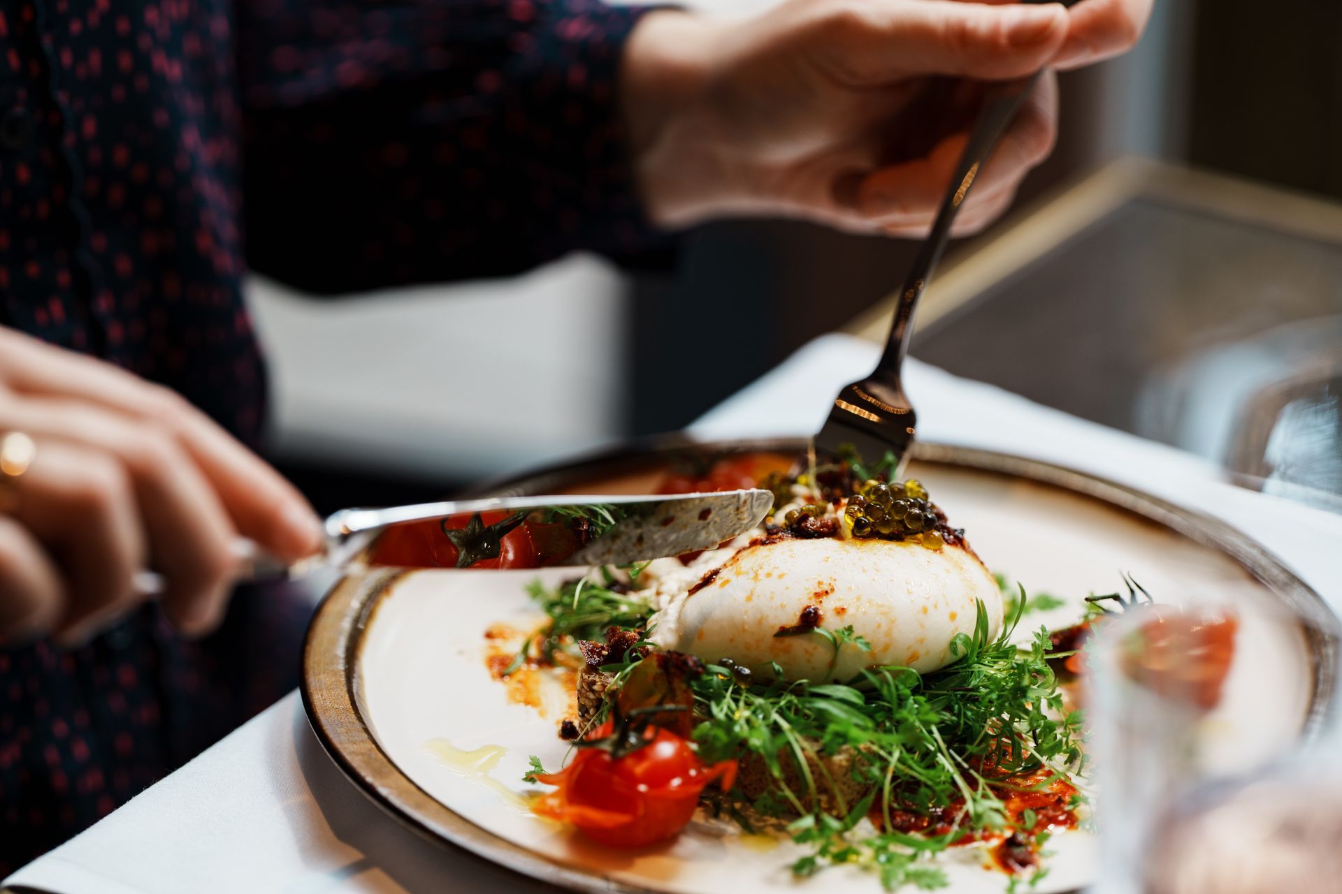 Eine Person isst mit Messer und Gabel in einem Restaurant.