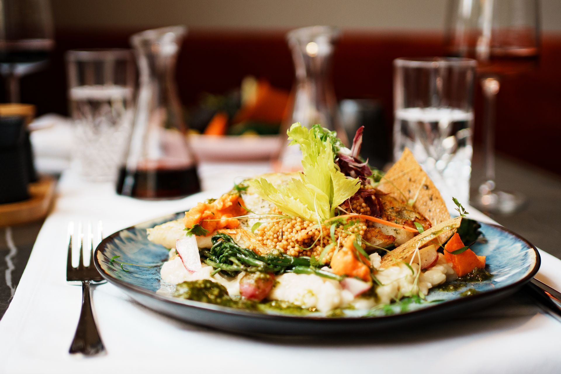 Ein mit Essen angerichteter Teller auf einem gedeckten Tisch mit Rotwein-Karaffe.