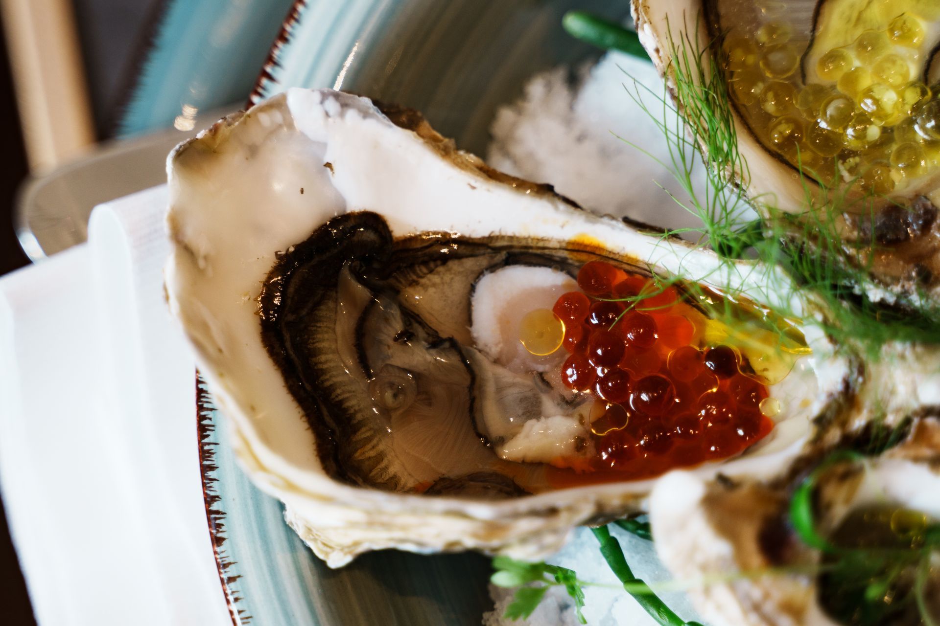 Eine Nahaufnahme einer Auster mit rotem Kaviar auf einem Teller.