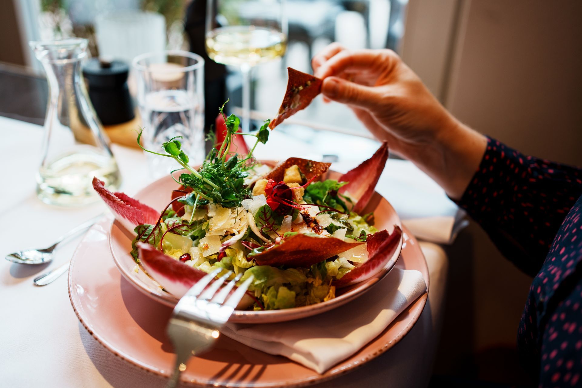 Eine Person isst in einem Restaurant einen Salat.