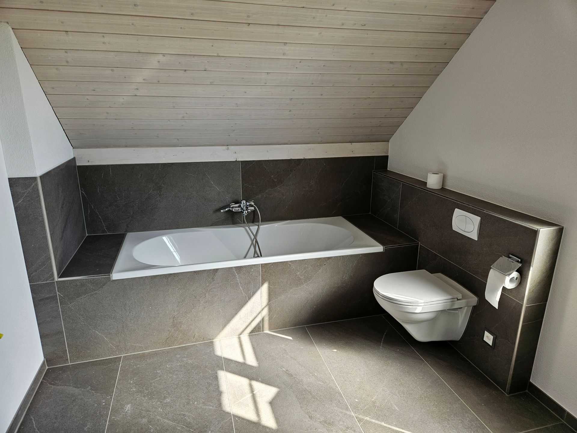 Moderne, geflieste, ebenerdige Dusche mit Regenduschkopf und Haltegriff