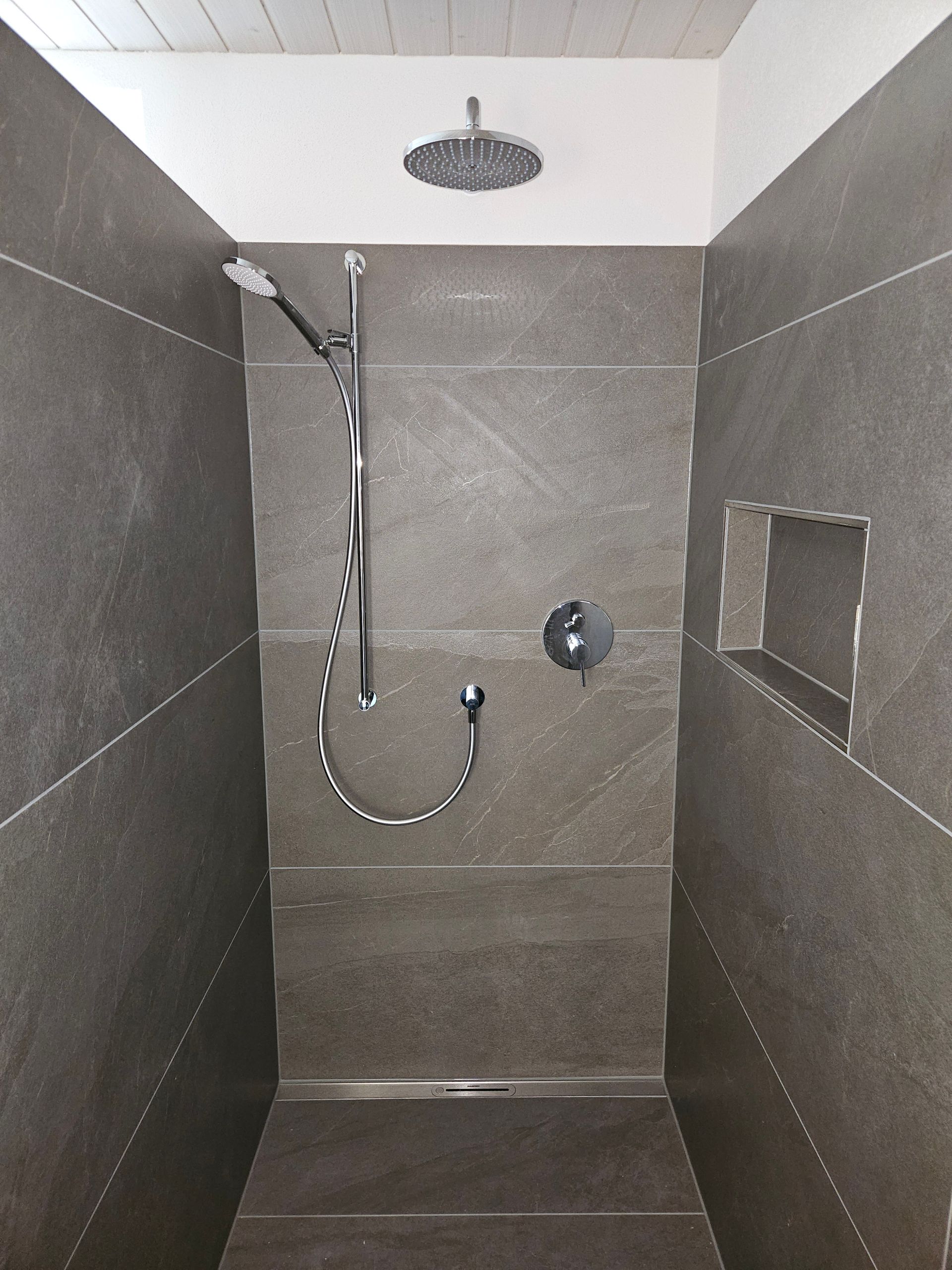 Öffentliche Toilette mit zwei Waschbecken, Spiegeln, roten Fliesenwänden und einer Person, die ein Selfie im Spiegel macht.