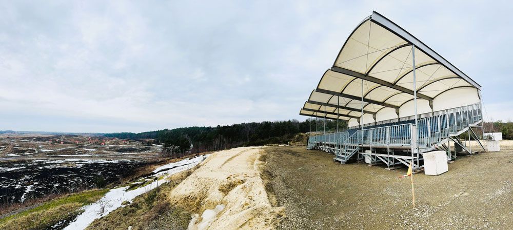 Viewpoint pavilion overlooking a black and gray landscape and forest under an overcast sky.