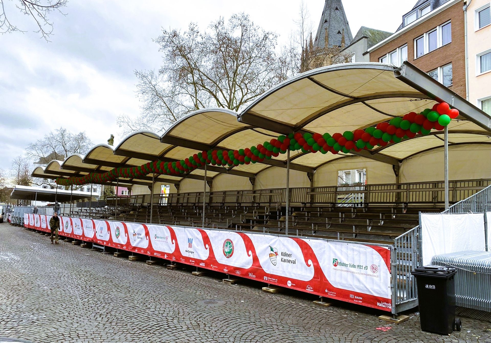 Ein überdachter Sitzbereich im Freien, der mit roten und grünen Luftballons und Bannern dekoriert ist.