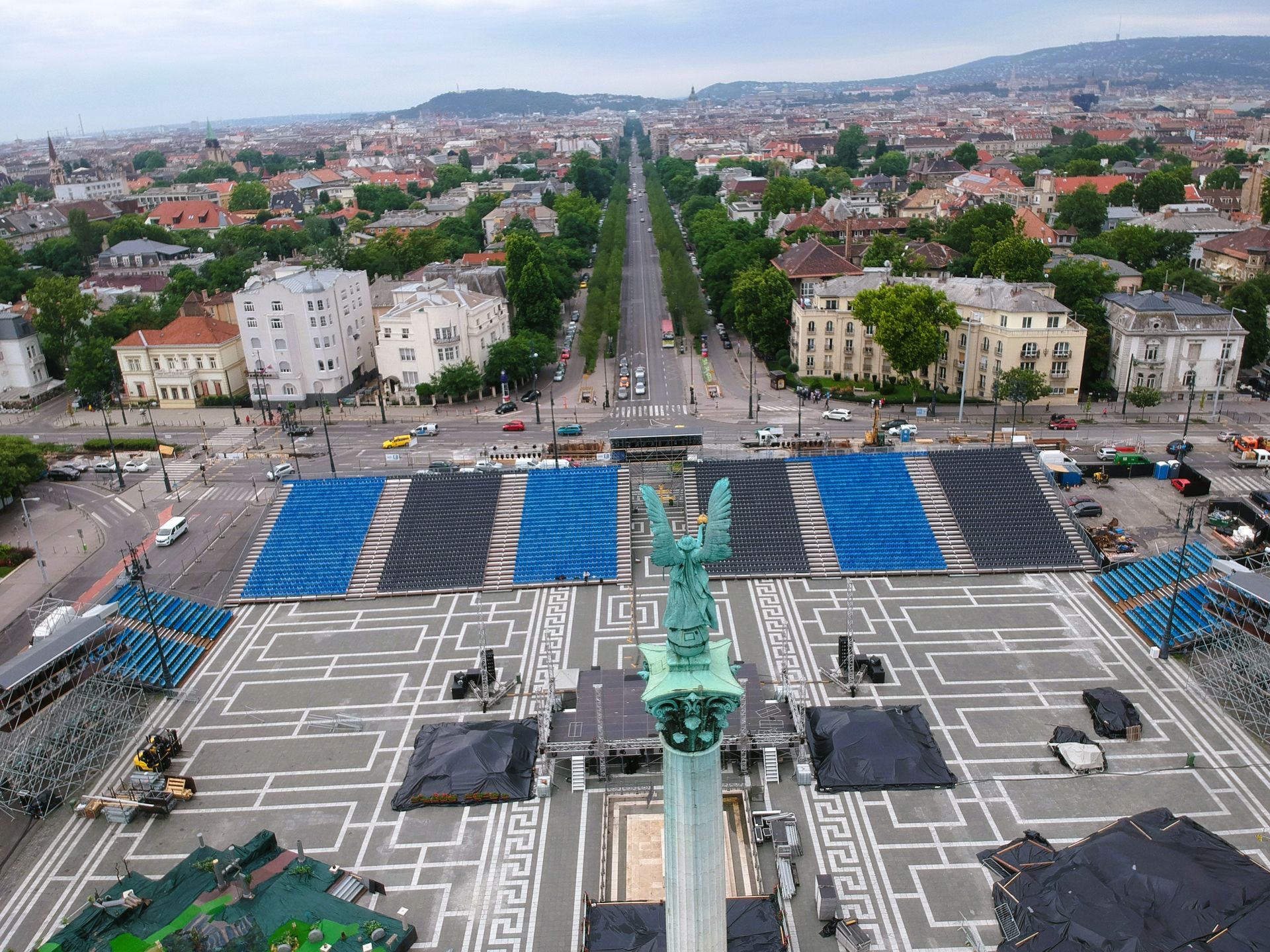 Luftaufnahme: Heldenplatz, Budapest, mit blau-schwarzen Sitzgelegenheiten für eine Veranstaltung. Im Hintergrund die Skyline der Stadt.