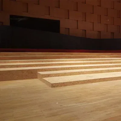 Zuschauerplätze in einem holzgetäfelten Zuschauerraum; Reihen von Holzstufen führen hinauf in einen dunklen Raum.