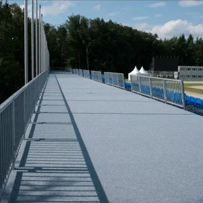 Ein langer, grauer, erhöhter Gehweg mit Metallgeländern und blauen Sitzgelegenheiten auf beiden Seiten.