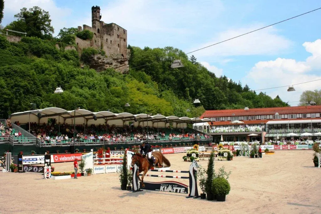 Springreiten vor Burgkulisse; Zuschauer auf Tribünen.