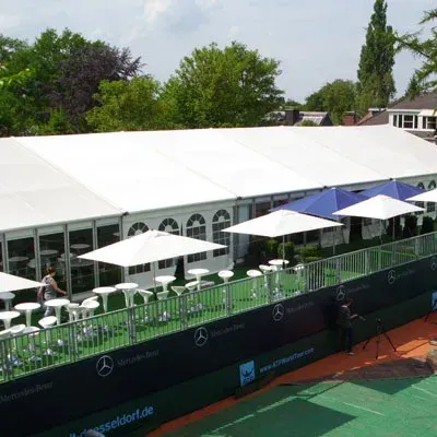 Tennisplatz mit weißen Sonnenschirmen, einem Zelt und Mercedes-Benz-Branding in Düsseldorf.