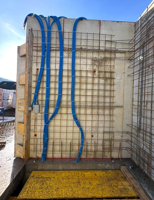 Eine weisse Doppelsteckdose mit einem schwarzen Stecker links und einem weissen Netzadapter mit Ladekabel rechts.