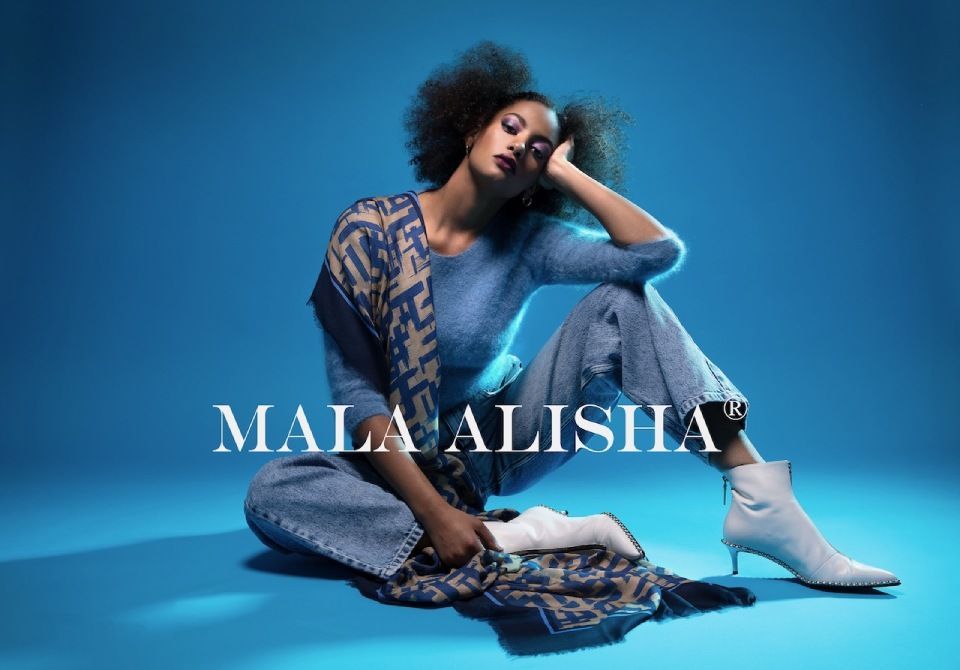 Eine Frau in einem blauen Outfit und weissen Stiefeln sitzt auf dem Boden. Foto von Mala Alisha