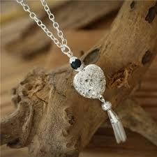 Auf einem Stück Holz sitzt eine Halskette mit einem herzförmigen Anhänger.