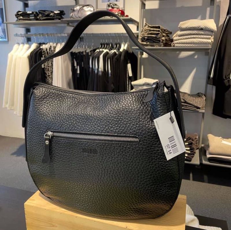 Eine schwarze Handtasche liegt auf einem Tisch.