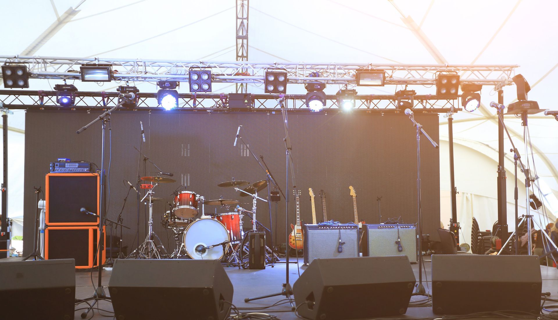 Un escenario vacío con una batería y guitarras encima.