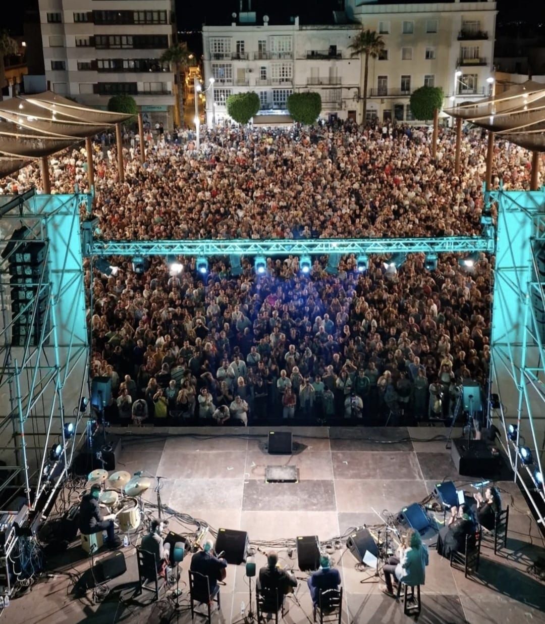 Un hombre está parado frente a un escenario con palmeras al fondo.