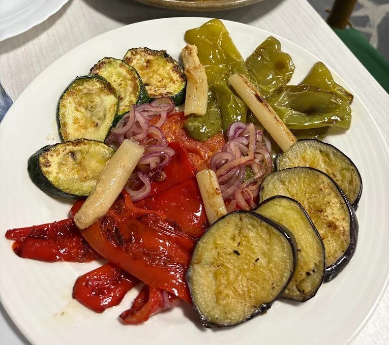 Verduras a la parrilla: calabacín, berenjena, pimientos, cebolla y espárragos en un plato blanco.