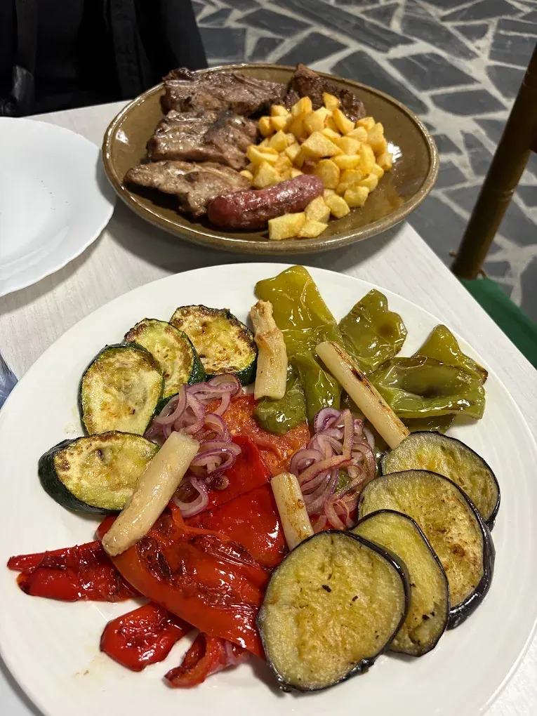 Platos de comida: carnes a la parrilla y patatas fritas; verduras a la parrilla: pimientos, berenjenas, calabacines.