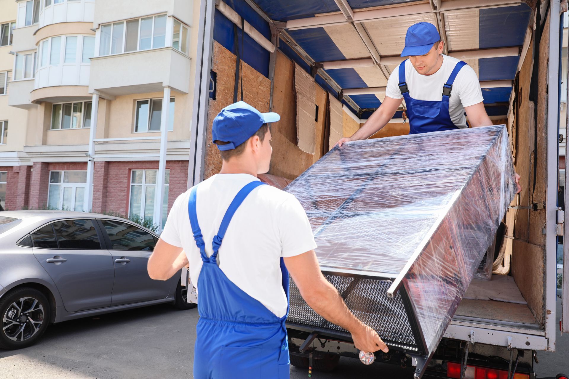 Deux déménageurs sortent un meuble emballé d'un camion