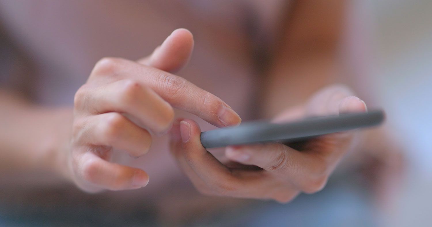 Eine Nahaufnahme einer Person, die ein Mobiltelefon benutzt.