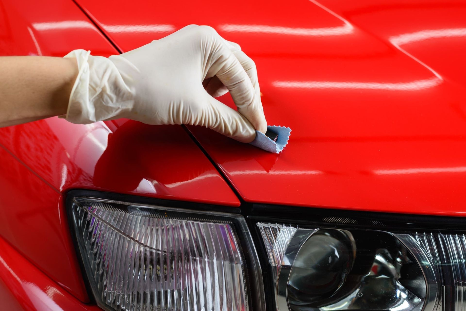Una persona está puliendo el capó de un coche rojo.