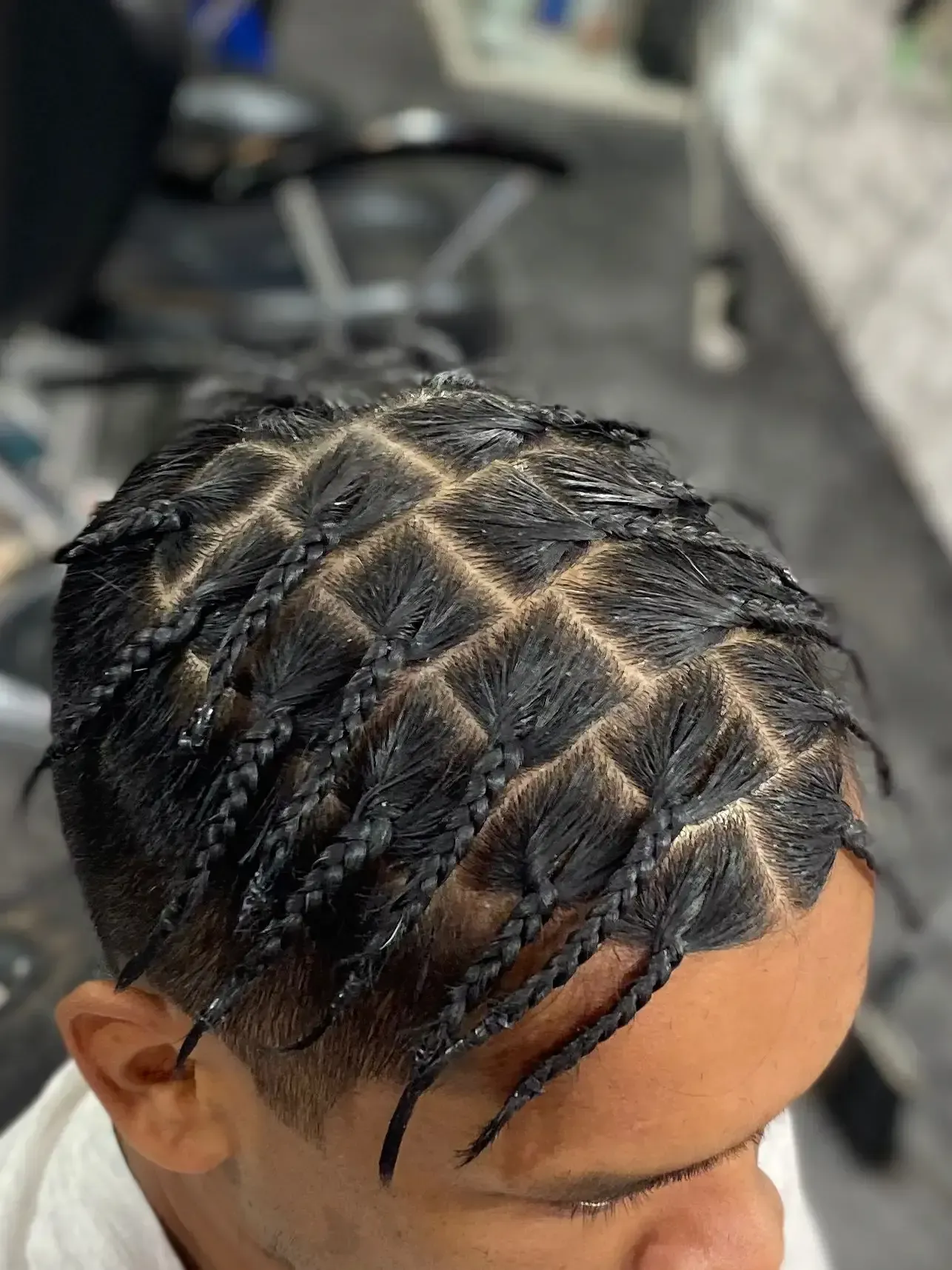 Primer plano de la cabeza de una persona con un peinado trenzado con patrón de diamantes, trenzas negras.