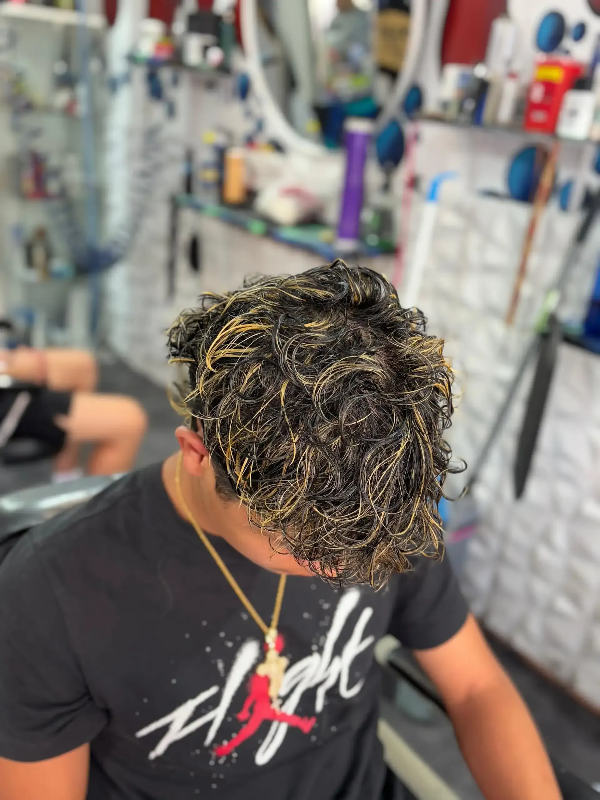 Persona con cabello texturizado teñido de rubio sentada en una barbería.