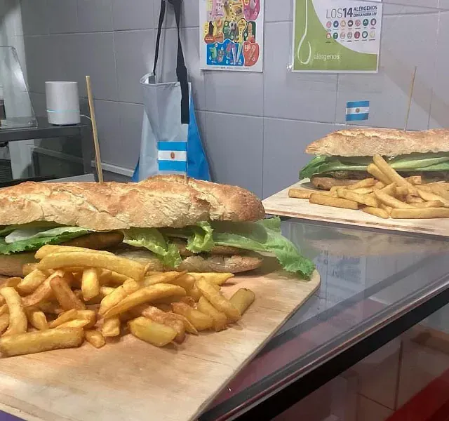 Dos sándwiches y papas fritas en una tabla de cortar de madera.