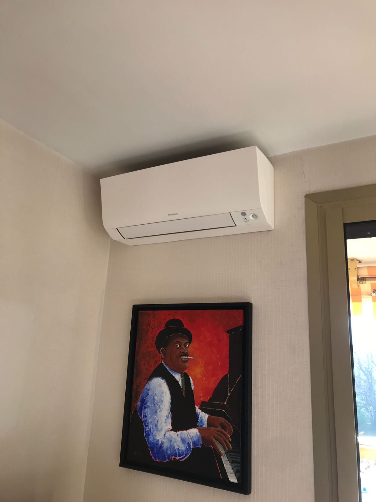 Climatiseur fixé au mur au dessus d'un cadre tableau
