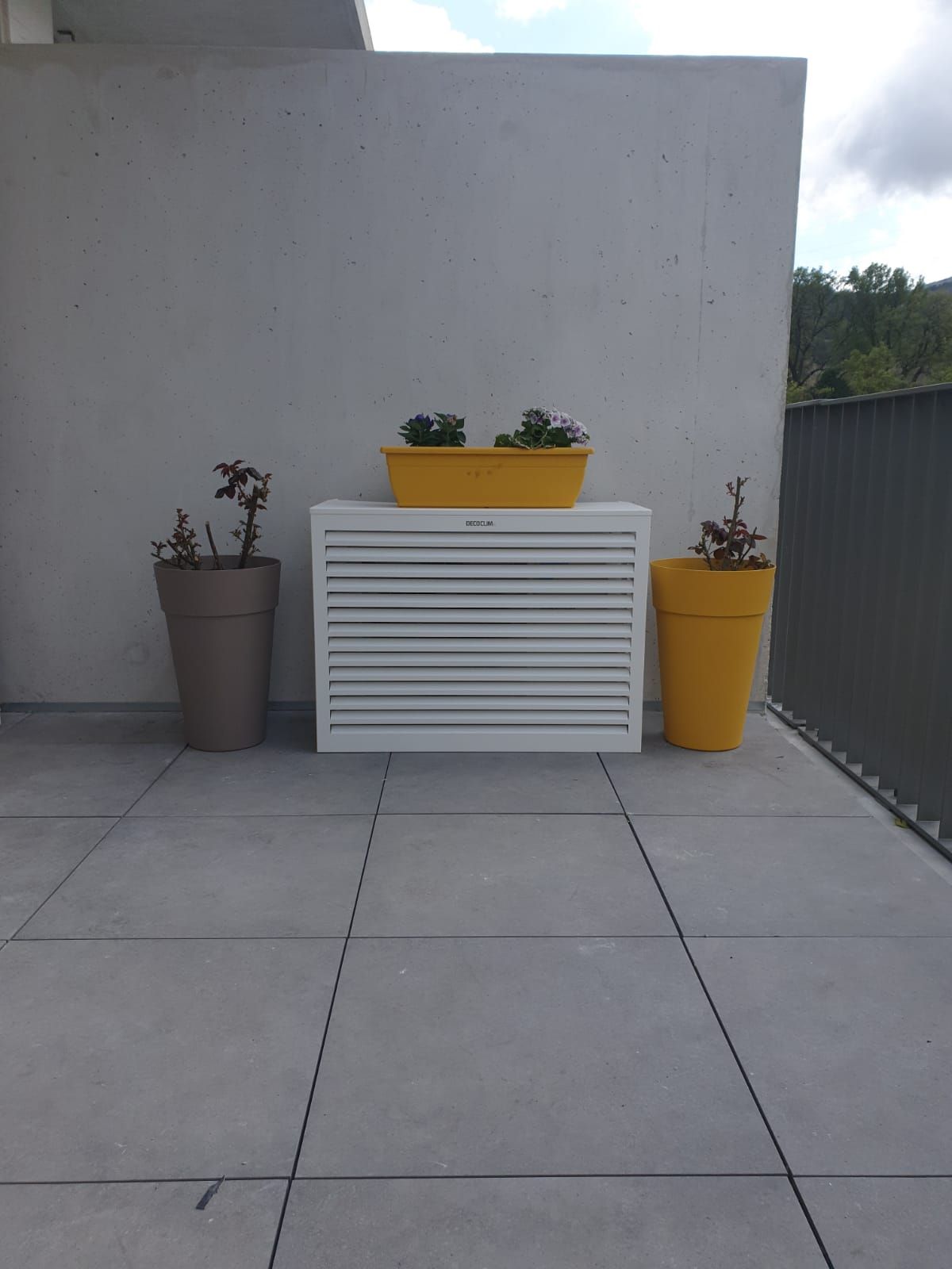 Pompe à chaleur dans une terrasse près de pots de fleurs