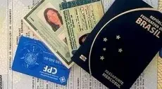 Un pasaporte, una licencia de conducir y una tarjeta CPF están colocados encima de una hoja de papel.