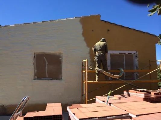 Un hombre está pintando con aerosol el costado de un edificio.
