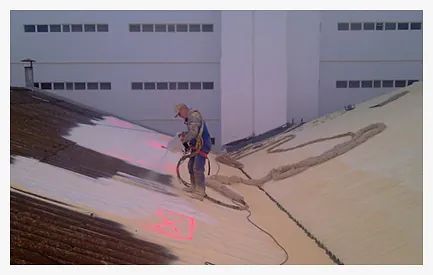 Un hombre está rociando espuma sobre el techo de un edificio.