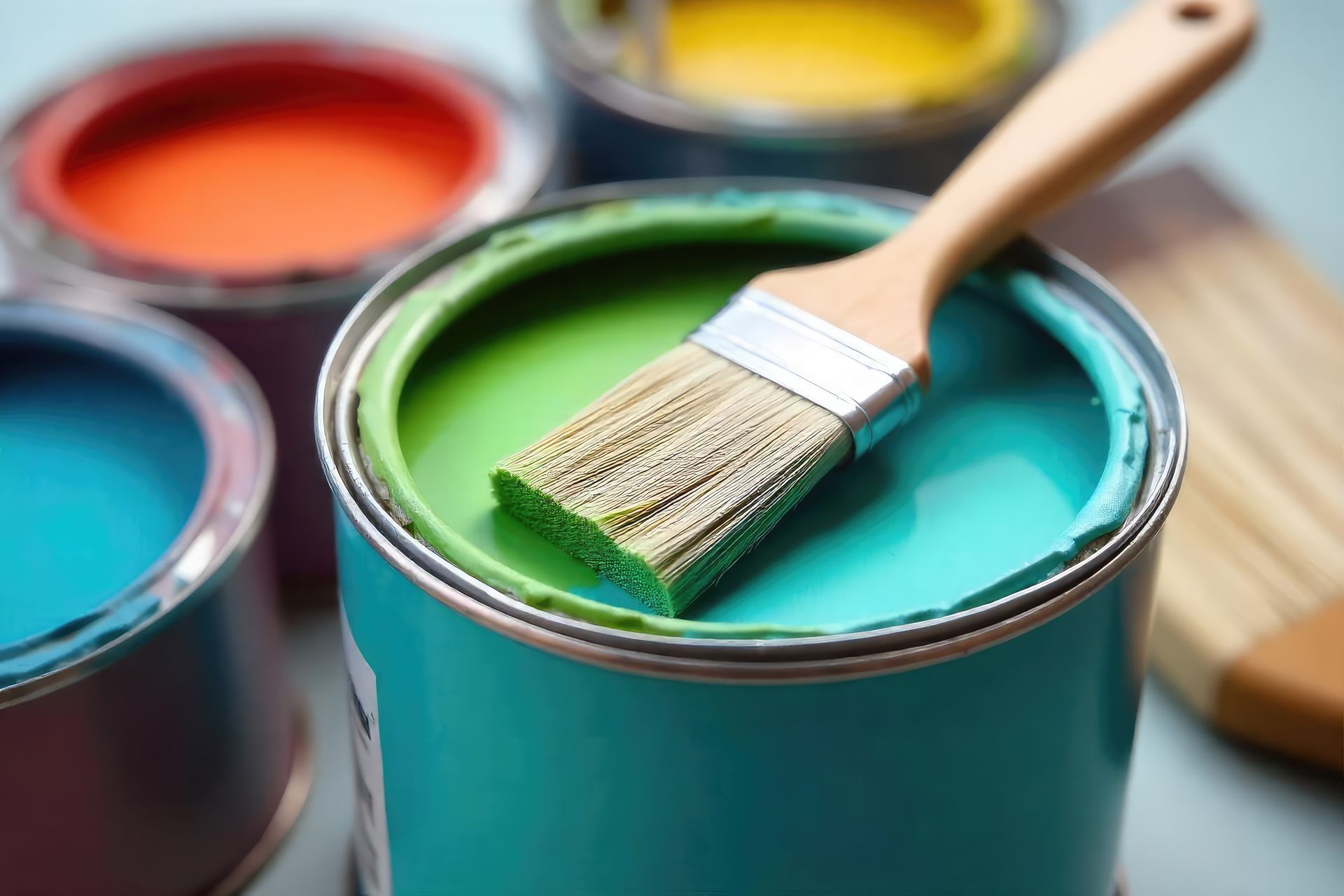 Des pots de peinture avec des pinceaux de couleurs variées. Un pot vert contenant un pinceau est visible au premier plan.