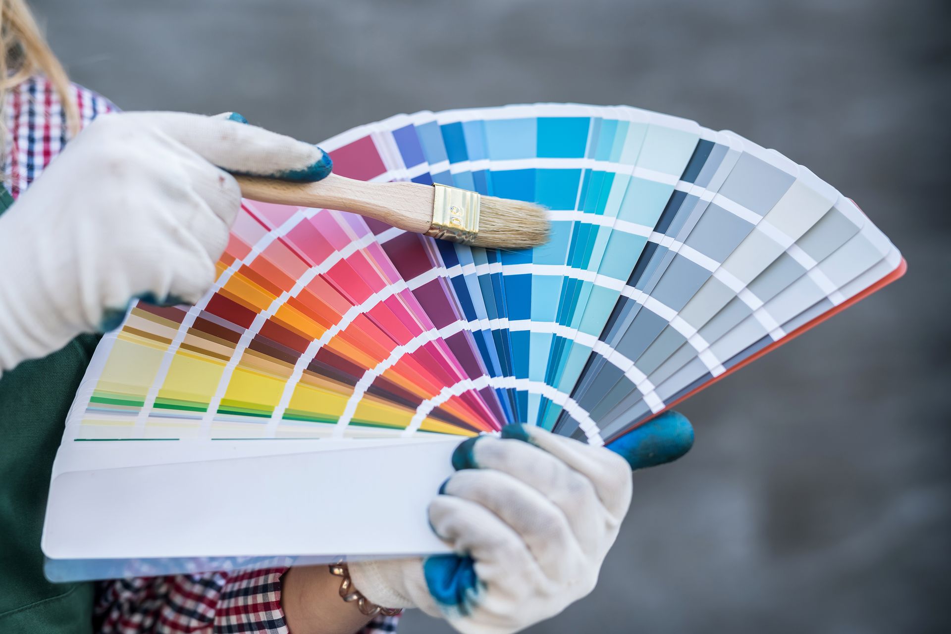 Personne portant des gants tenant un éventail de peinture et un pinceau.