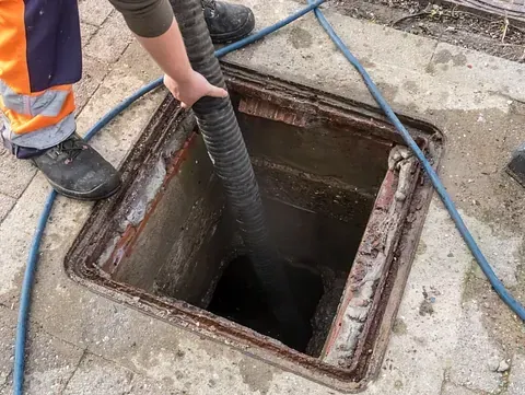Una persona está bombeando agua hacia la tapa de un pozo.