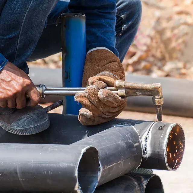 Un hombre está cortando un tubo con un soplete.