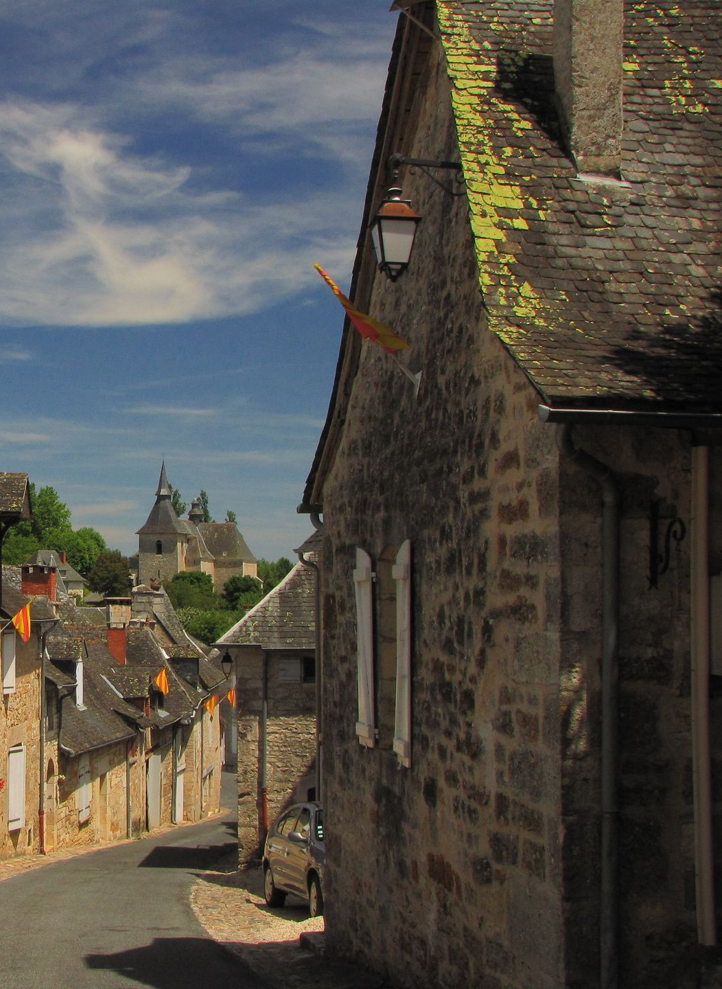 Vieilles maisons en pierre, toitures en ardoises verdies avec mousses sous un ciel bleu