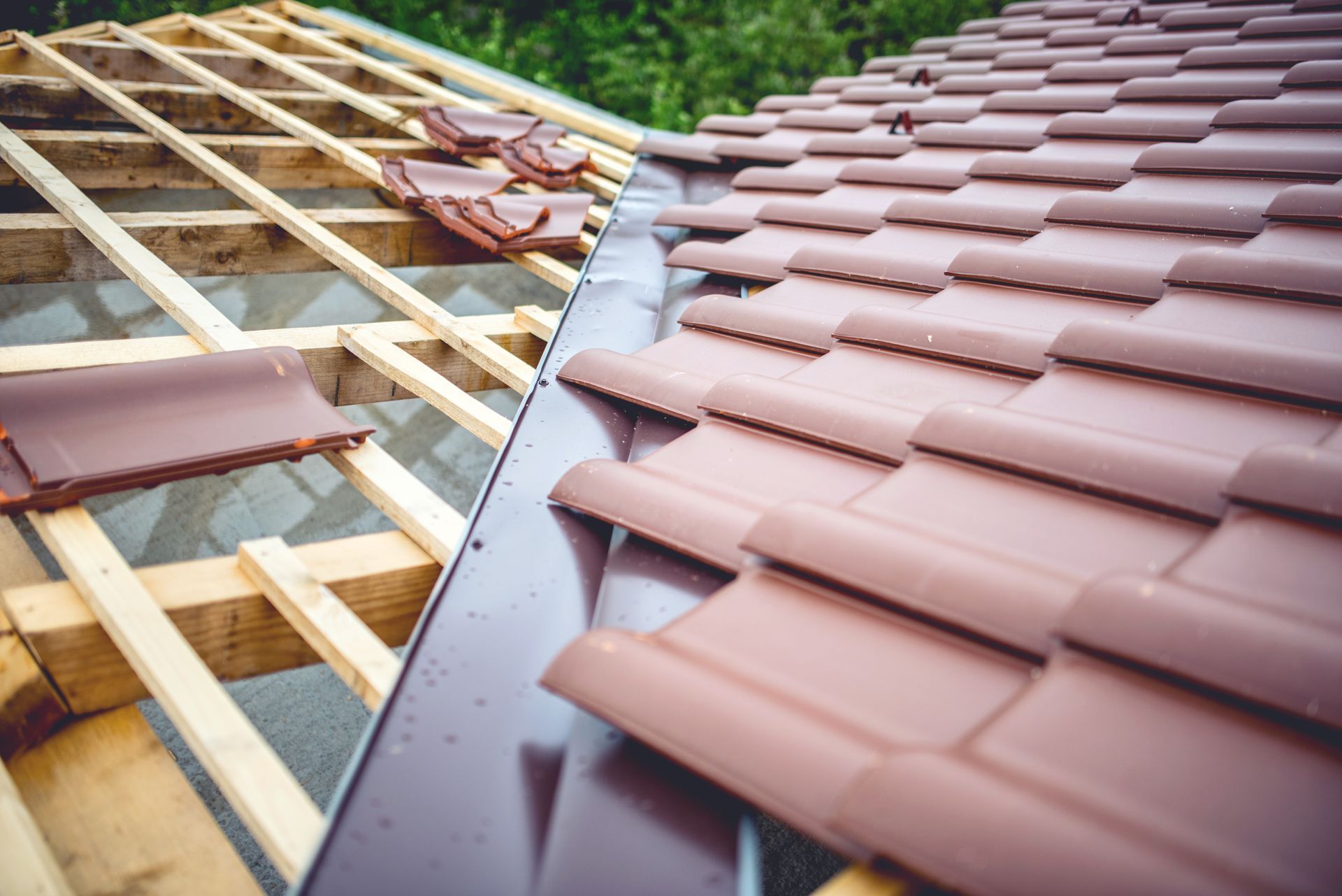 Toiture en construction avec charpente en bois apparente à côté des bardeaux bruns installés.
