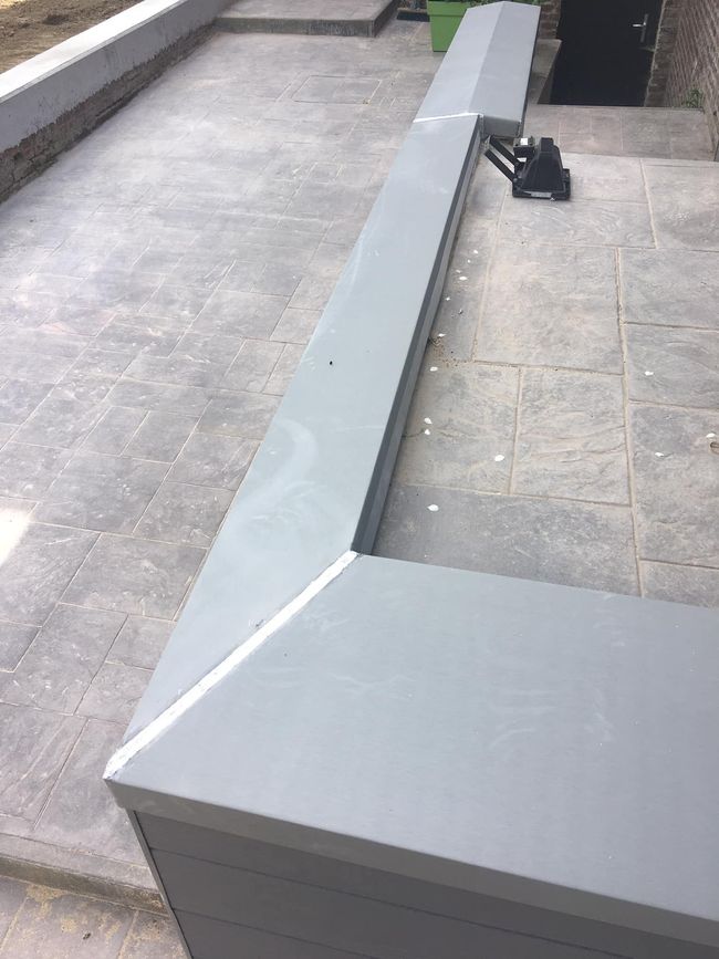 Parapet et corniche de toit en béton gris avec un support noir sur la surface carrelée.