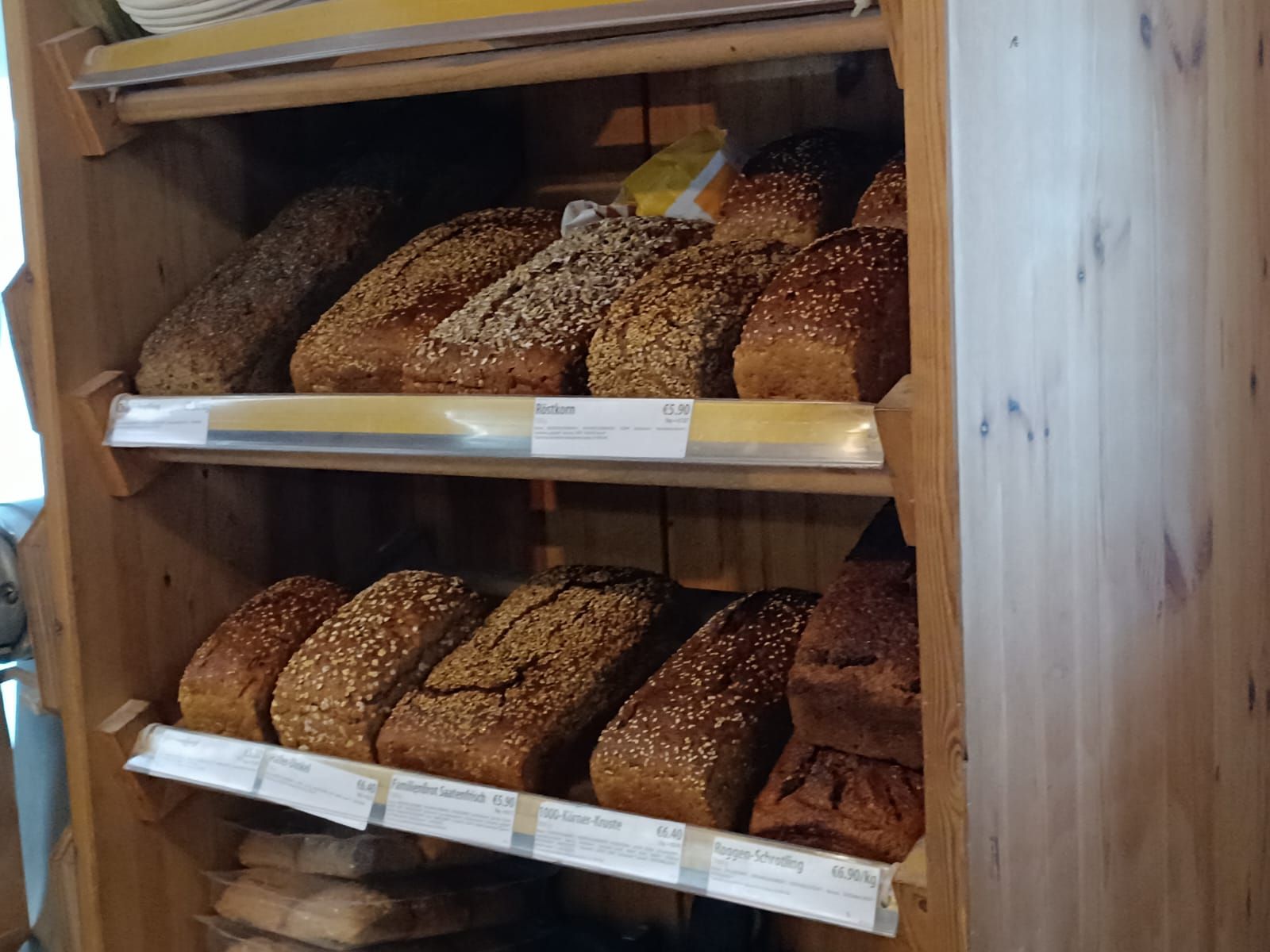 In einer Bäckerei hält eine Frau einen Laib Brot in einer Papiertüte.