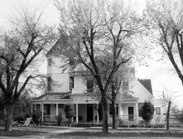 A black and white photo of a house with trees in front of it