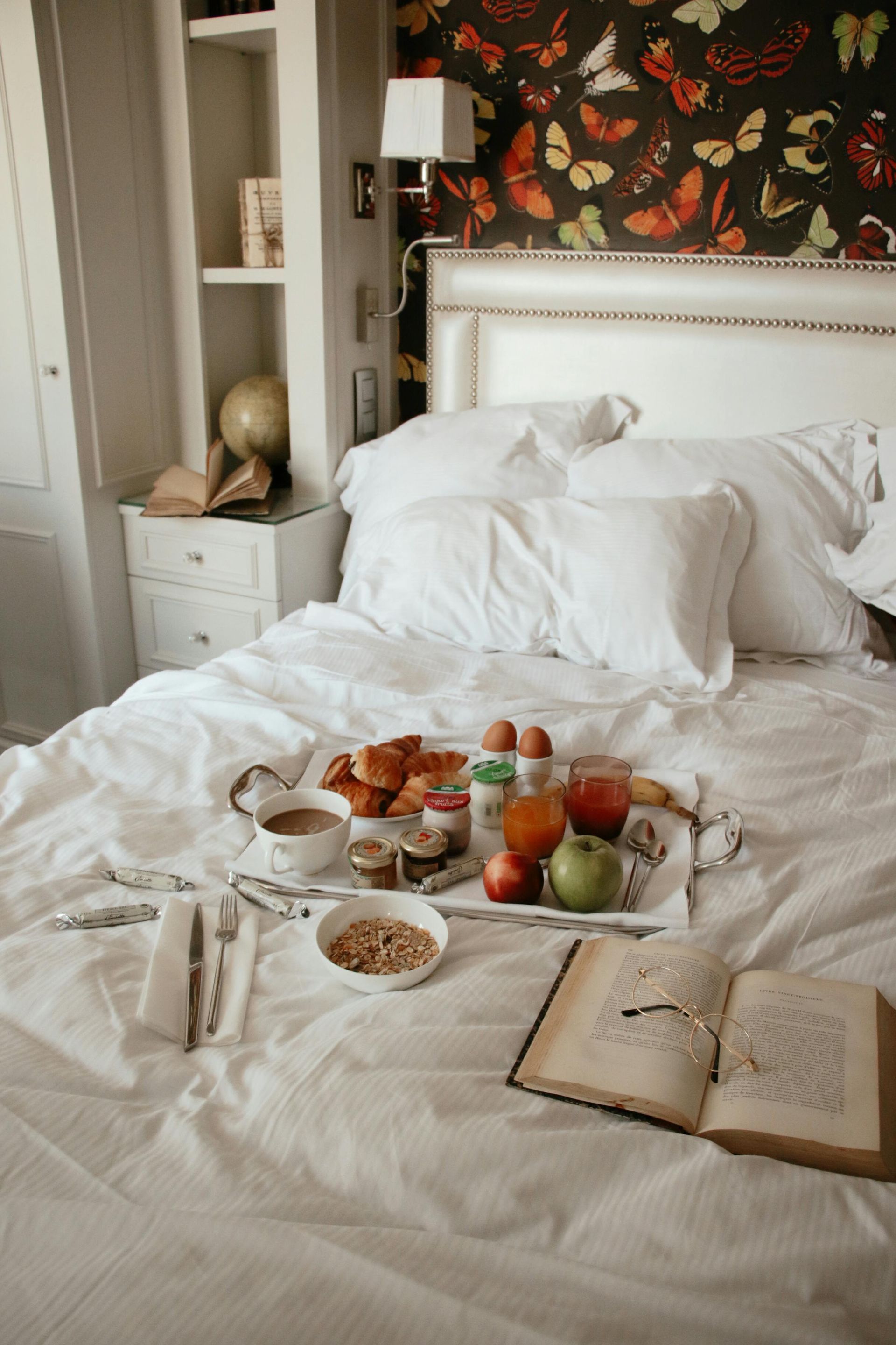 A bed with a tray of food and a book on it.